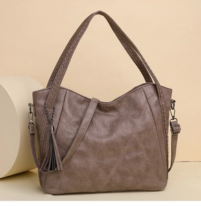 Macro detail of brown quilted leather handbag featuring woven handles and stylish tassel