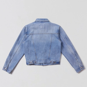 Dettaglio della giacca di jeans blu chiaro lavato con schizzi di vernice e cuciture posteriori