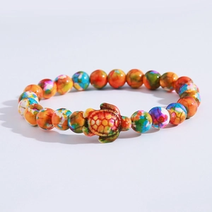Macro shot of colorful beaded bracelet featuring a detailed turtle charm on white background