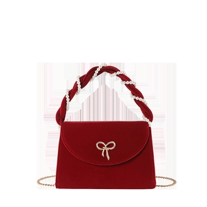 Red velvet handbag with pearl handle, gold bow buckle and chain strap on white background