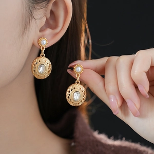 Detail of vintage gold earrings with pearls and crystals shown on a model's ear