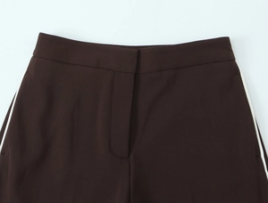 Detail of dark brown trousers waist featuring side stripes and a clean invisible placket