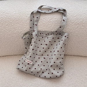Gros plan du sac en toile avec motif à pois vintage et détails de nœuds brodés