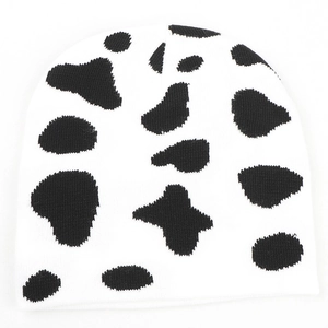 Detailed view of knitted winter beanie featuring classic black and white cow print pattern