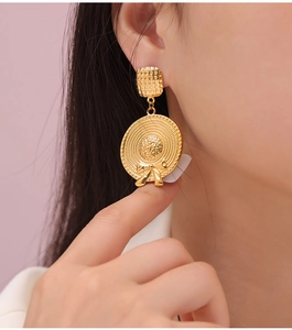 Close-up of gold-plated titanium steel earrings with a woven straw hat and bow design