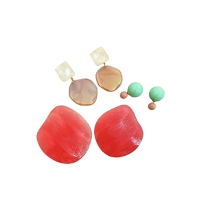Three pairs of resin geometric earrings in red, amber and mint green on white background
