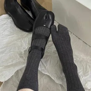 Grey vertical striped tabi socks paired with black leather Mary Jane split-toe shoes