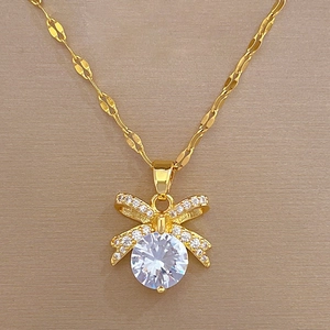 Detail of gold bow necklace with a large round cubic zirconia and pavé-set stones