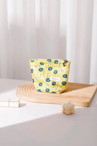 Detailed macro of yellow quilted flower makeup bag with golden floral zipper pull