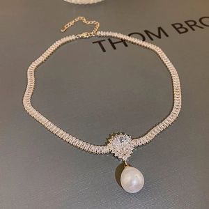 Detail of gold-plated necklace with rectangular zircon and teardrop pearl pendant