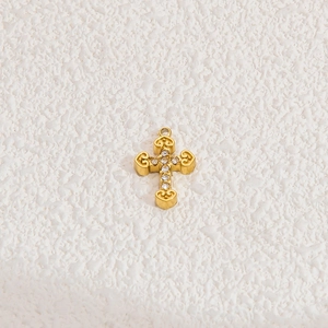 Macro detail of golden cross pendant featuring sparkling white zircon stones and metal ring