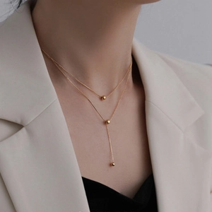 Detail of double-layer gold titanium steel necklace with elegant sphere pendants