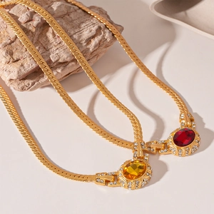 Vintage gold snake chain necklace with oval red and yellow rhinestones on stone background