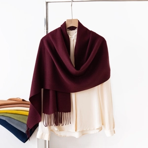 Dettaglio di una sciarpa bordeaux effetto cashmere con frange su una camicia beige