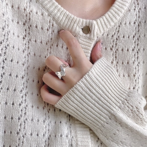 Detailed close-up of a silver irregular lava-texture ring worn on a model's finger