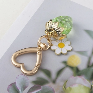 Detailed macro view of green resin strawberry and heart clasp on the keychain
