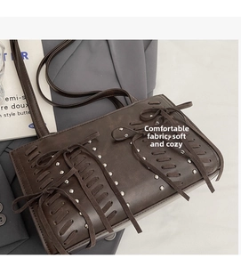 Detail of dark brown PU leather shoulder bag with bow weaving and silver rivet accents