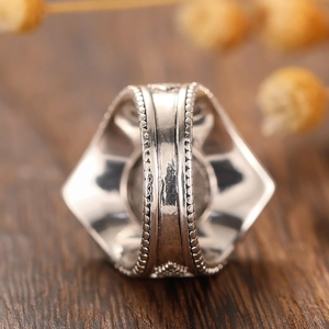 Vue macro d'une bague large rétro en métal avec motifs géométriques et textures gravées