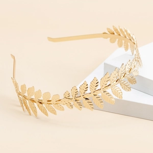 Detailed view of a golden leaf-shaped metal headband on a minimalist white stand