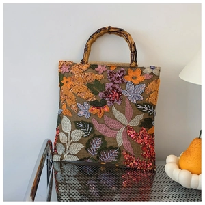Detail of linen handbag featuring bamboo handles and 3D floral embroidery with sequins