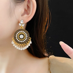 Dettaglio macro di orecchini vintage a cerchio con strass luccicanti e nappe di perle