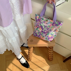 Dettaglio della borsa in tela a fiori viola con bottone in metallo e etichetta Sora