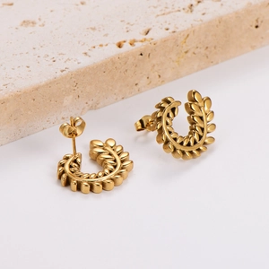 Golden C-shaped wheat ear earrings set on a minimalist stone base display
