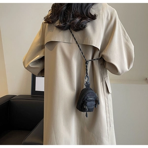 Mini black backpack-style crossbody bag with leopard print strap worn on a model