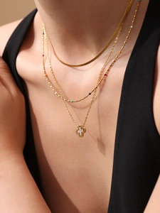 Close-up of golden triple-layered necklace with snake chain and lucky clover pendant