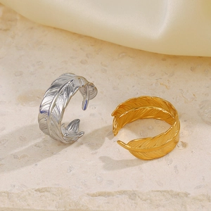 Adjustable stainless steel feather rings in gold and silver finish on marble surface