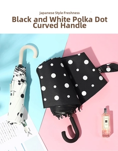 Close-up of J-shaped hooked handles on polka dot folding umbrellas for sun and rain