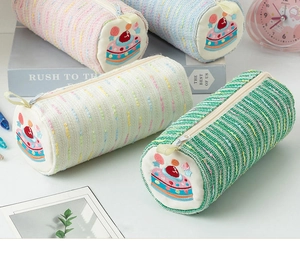Detail of colorful woven pencil cases with embroidered cream cake pattern on the round ends