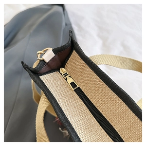 Detail shot of the golden zipper closure and textured khaki canvas on the tote bag