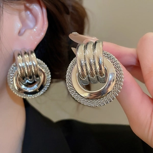 Détail de boucles d'oreilles rondes en métal argenté torsadé avec texture en maille