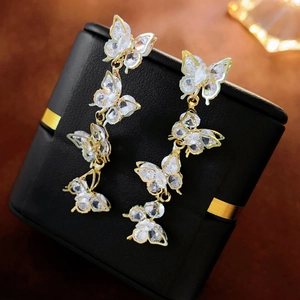 Macro shot of long gold butterfly earrings with sparkling cubic zirconia on black box