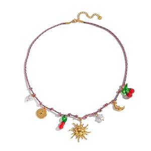 Detailed flat lay of bohemian woven necklace with gold sun pendants and resin cherries