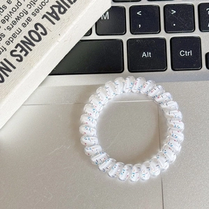 Detail shot of spiral telephone cord hair tie with colorful polka dots on white surface