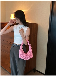 Close-up of pink woven knot shoulder bag with textured puffy handle and soft fabric