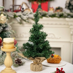 Close-up of a 30cm mini Christmas tree with pine needles and burlap base on a table