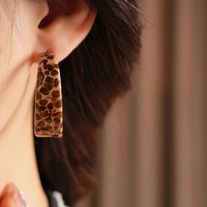 Close-up of a tortoiseshell acetate C-shaped earring worn on a model's ear