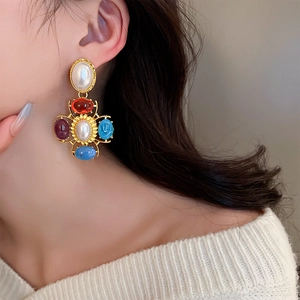 Détail de boucles d'oreilles style palais vintage avec perles et gemmes colorées
