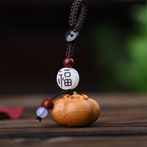 Macro shot of hand-carved wooden pumpkin charm with Futian engraved bead and woven cord