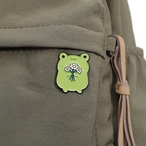 Cute green enamel frog pin with daisies on canvas bag, charming animal brooch accessory