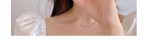 Primo piano di una collana con ciondolo a curva sorridente in argento sul collo