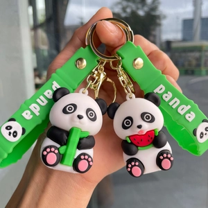 Close-up of panda keychains with green wristbands holding bamboo and watermelon pieces