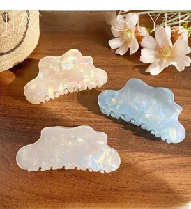 Detailed view of iridescent cloud hair claws in cream white, ice blue, and soft pink