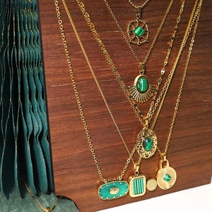 Gros plan de colliers en or 18 carats avec pendentifs en malachite sur un présentoir en bois