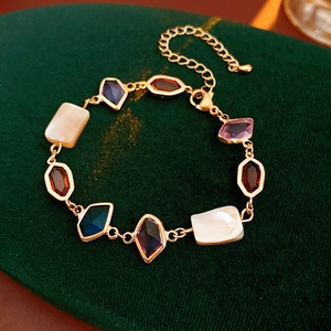 Détail du bracelet vintage doré avec gemmes colorées sur fond velours vert foncé
