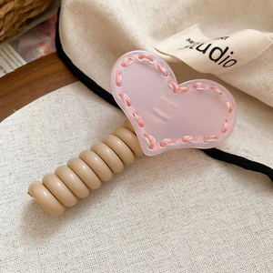 Détail du pendentif coeur en acrylique rose avec cordon élastique spirale beige