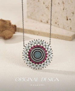 Detail of a round S925 silver pendant with multicolored gemstones on a gray metal chain